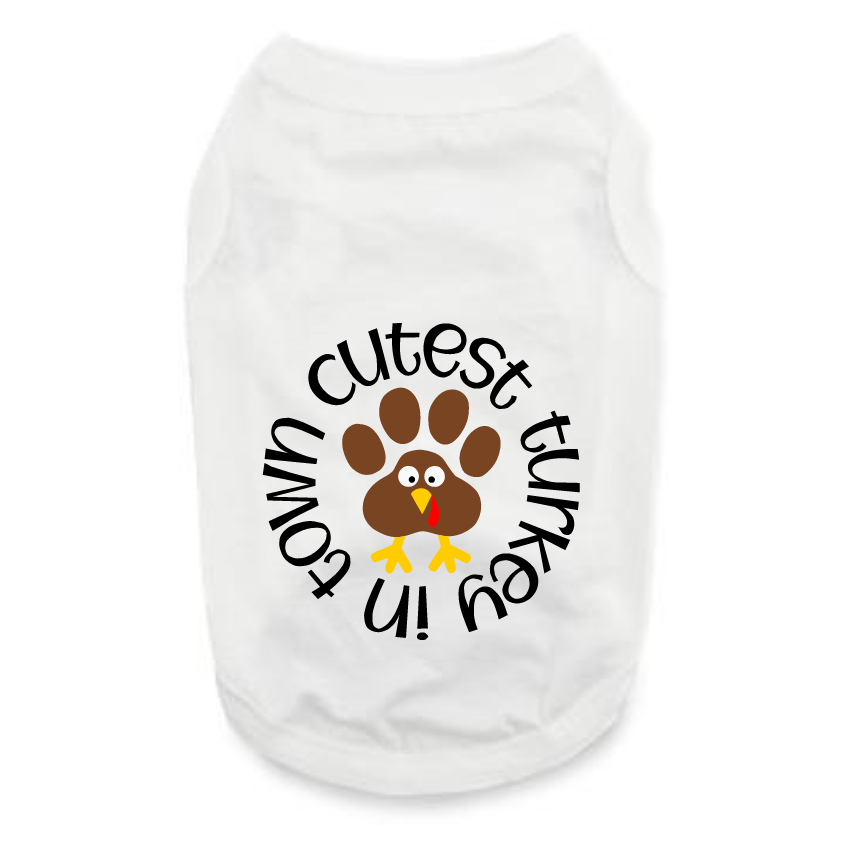The Cutest Turkey In Town pet shirt is a white tee with a playful graphic turkey featuring a paw print body and the phrase "cutest turkey in town"—perfect for festive dog apparel and Thanksgiving collections.